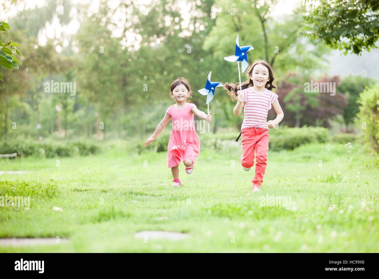 Due ragazze sorridenti con pinwheels in esecuzione sul campo Foto Stock
