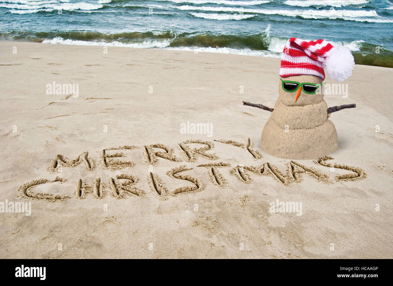 Buon Natale in spiaggia con sabbia di pupazzo di neve con cappello Foto Stock