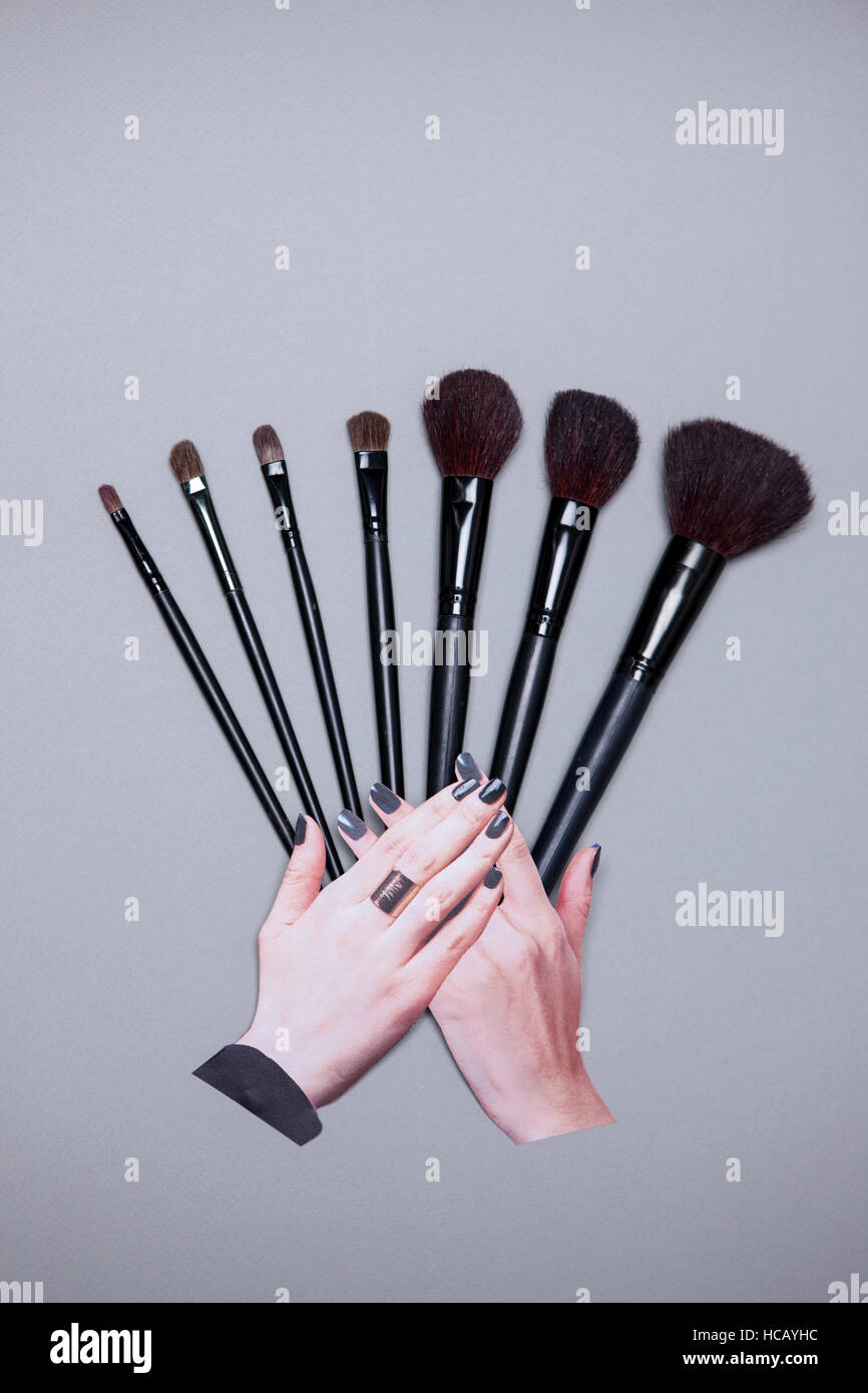 Mani toccano le spazzole cosmetiche Foto Stock