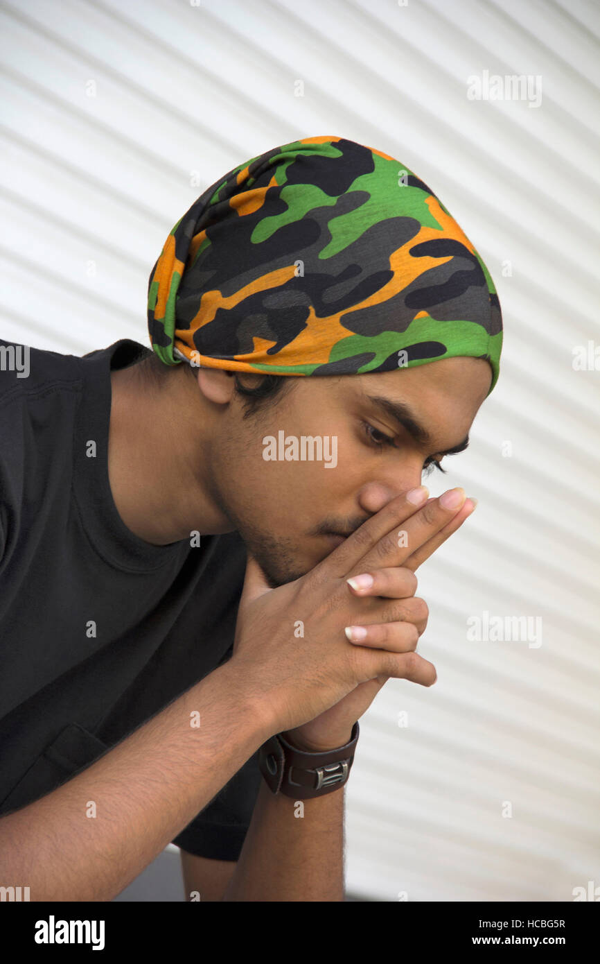 Close-up di un giovane ragazzo indiano seduto in pensiero profondo Foto Stock