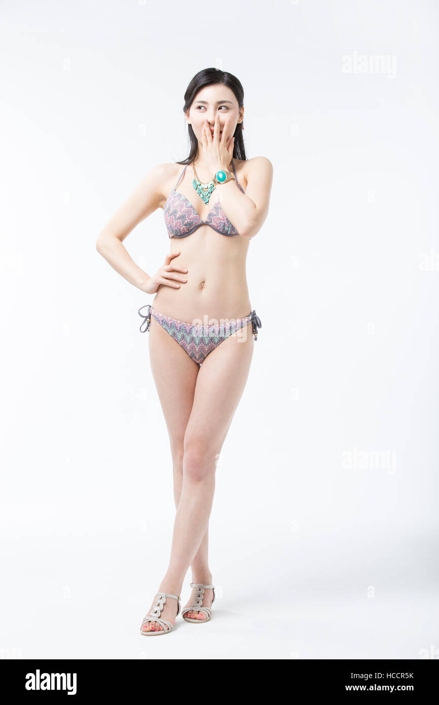 Giovane donna in bikini in posa che copre la bocca Foto Stock