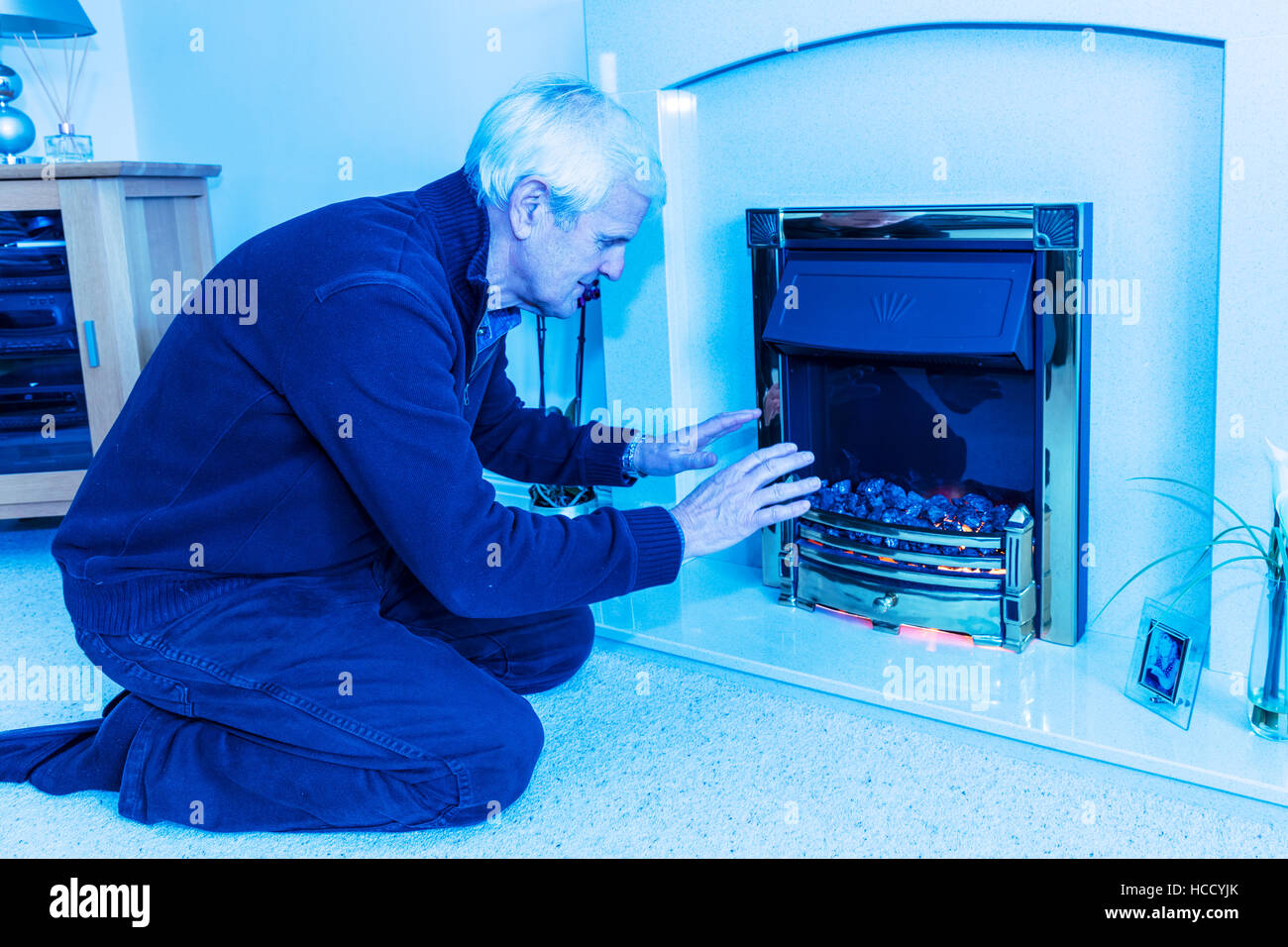 OAP cercando di mantenere caldo il riscaldamento le mani vicino al fuoco conservando le fatture verso il basso non può permettersi il riscaldamento bill elevata di gas le bollette di energia REGNO UNITO Inghilterra Foto Stock