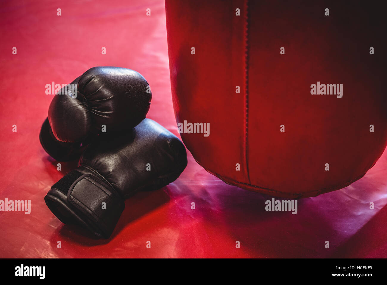 I guantoni e sacco da boxe sulla superficie rossa Foto Stock