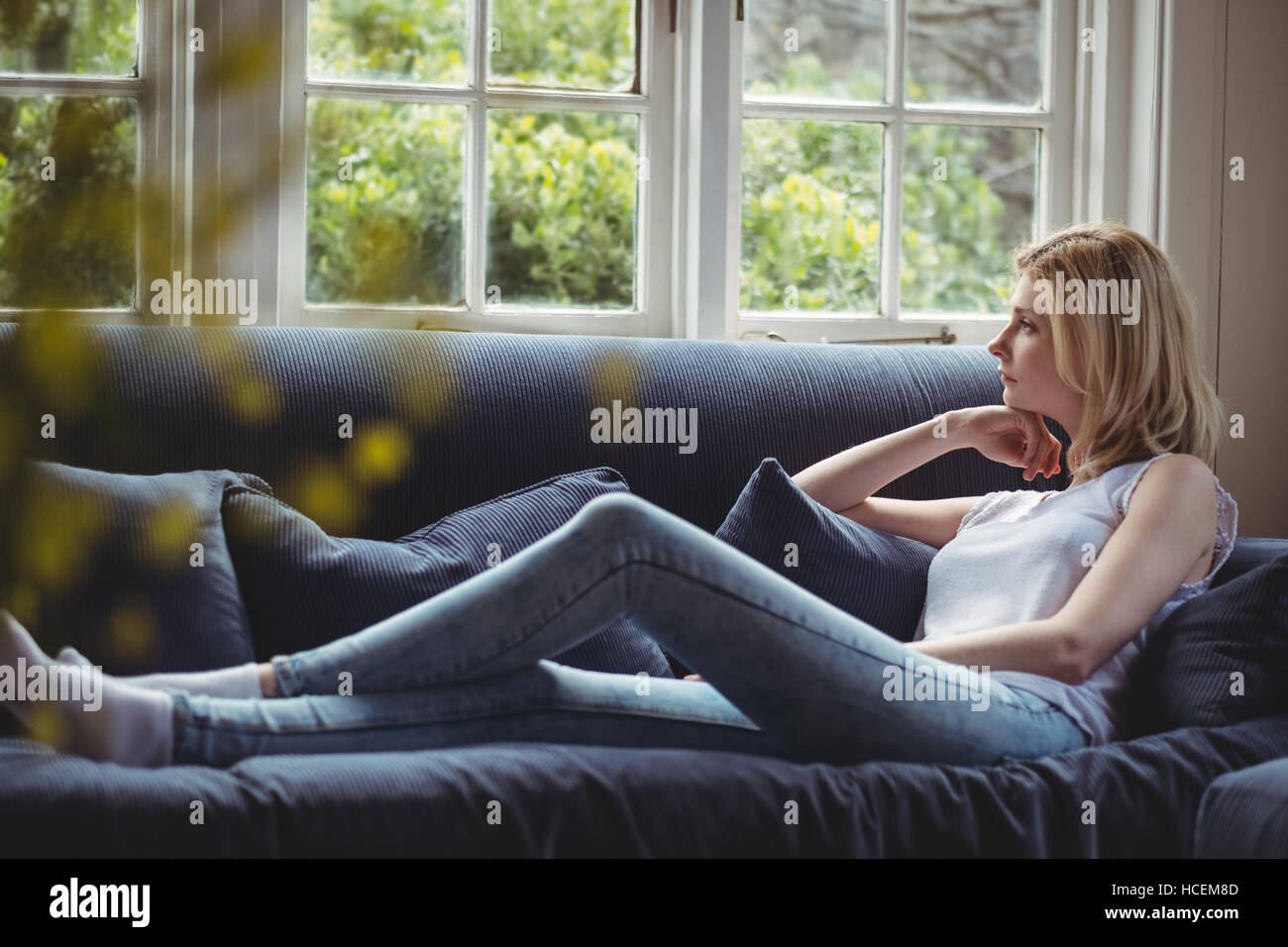 Premurosa donna seduta sul divano nel soggiorno Foto Stock