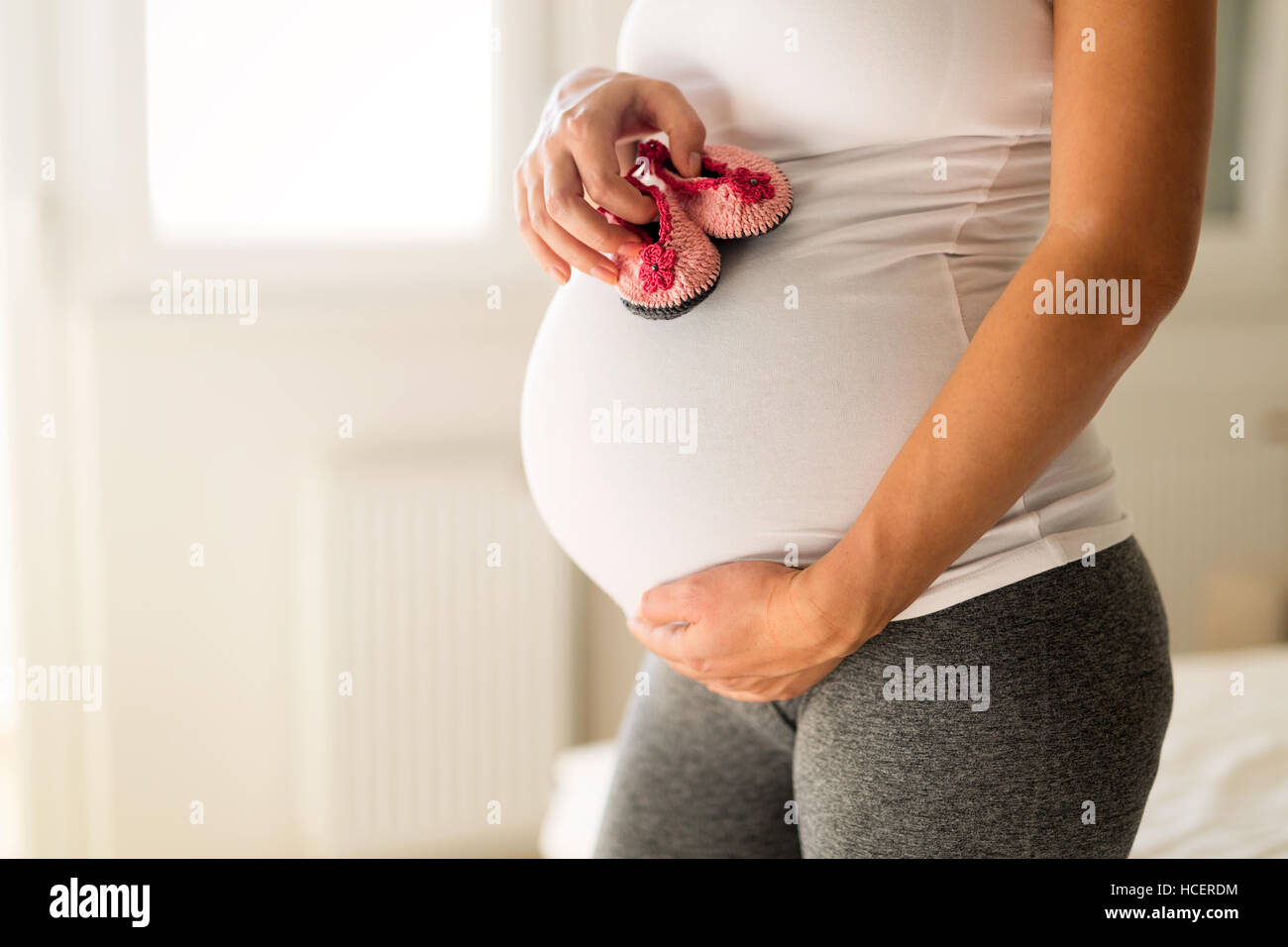 Donna incinta tenendo poco scarpe neonato Foto Stock
