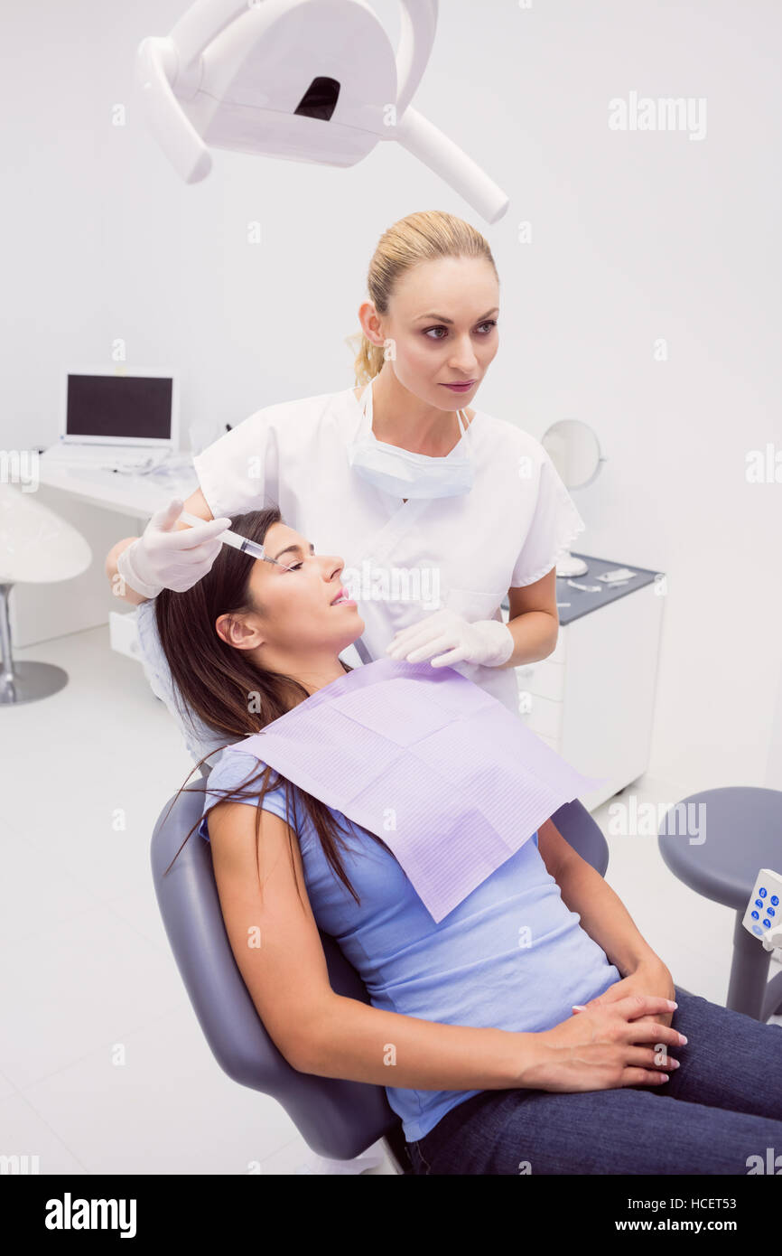 Dentista tenendo una siringa mentre l'esame paziente Foto Stock