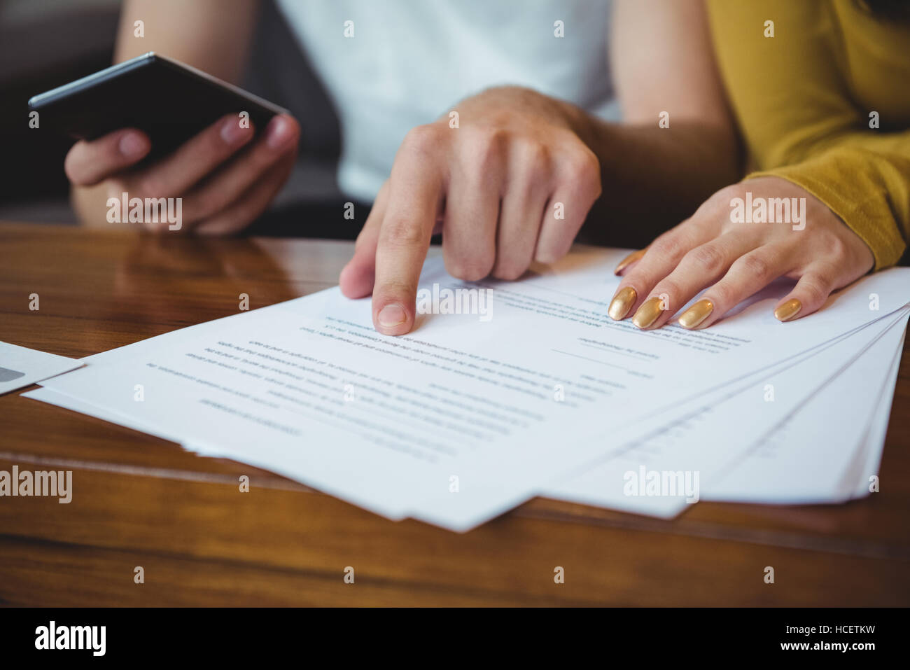 Giovane discutendo con documenti finanziari e Calcolatrice in salotto Foto Stock