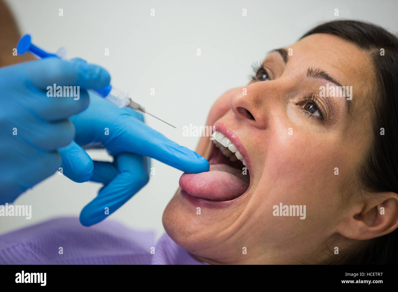 Dentista dando l'iniezione nel paziente femmina Foto Stock