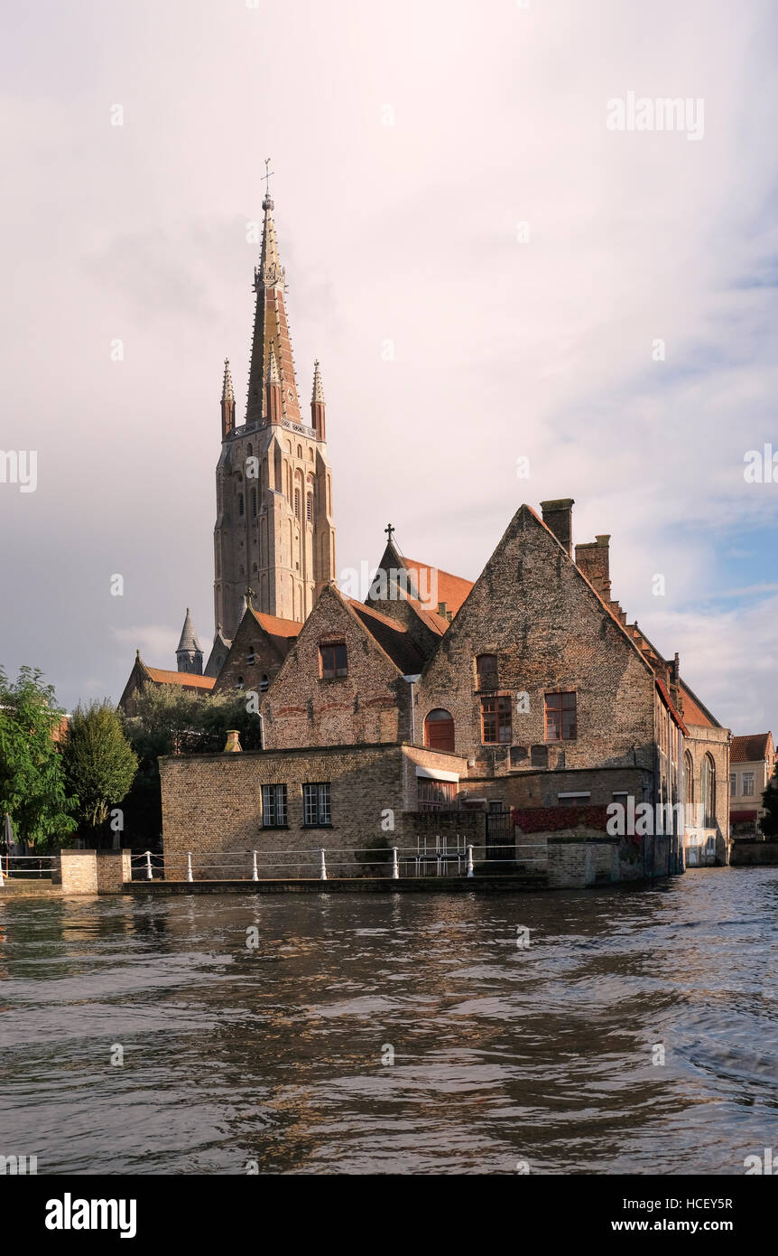 Il Sint-Janshospitaal, Saint John's Hospital, Bruges. Iniziato nel XII secolo, visto dal canale, con la torre di Onze-Lieve-Vrouwekerk, o della Chiesa Foto Stock