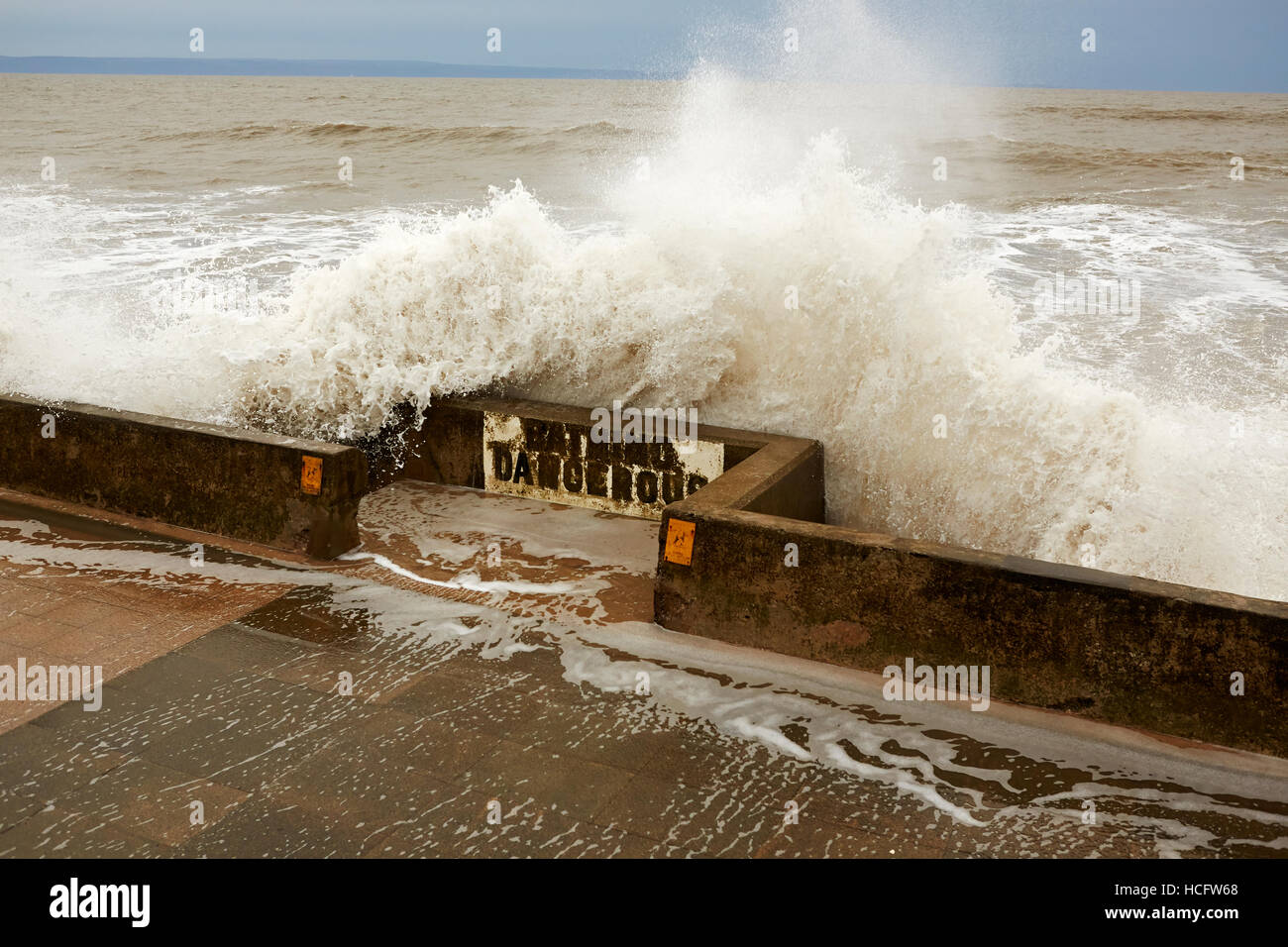 Onde che si infrangono sulla parete del mare e balneazione "pericolose" segno, Porthcawl, Wales, Regno Unito Foto Stock