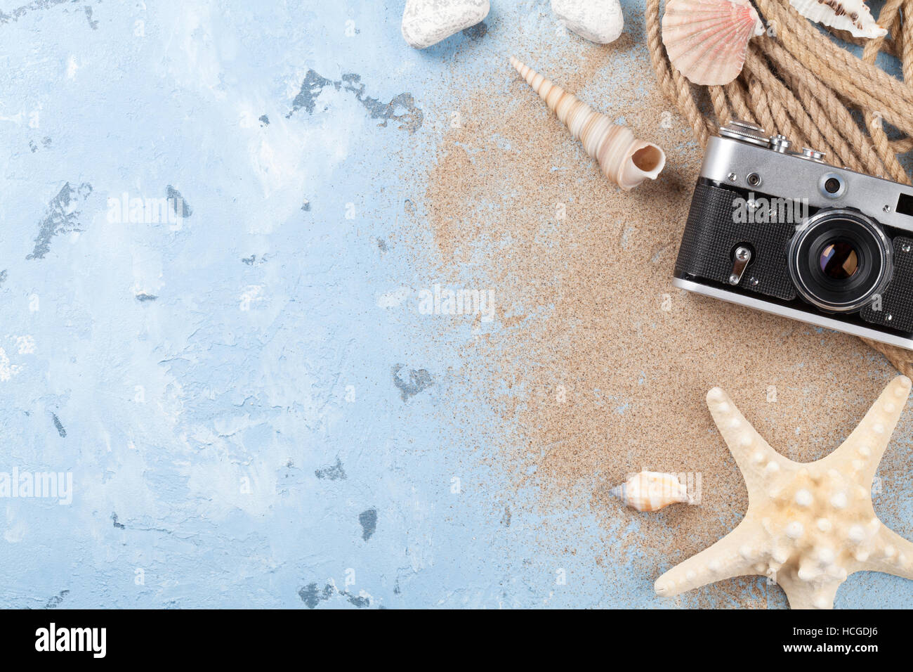 Vacanza al mare sullo sfondo. Fotocamera, stelle marine e seachells su uno sfondo di pietra con sabbia. Vista da sopra con copia spazio. Foto Stock