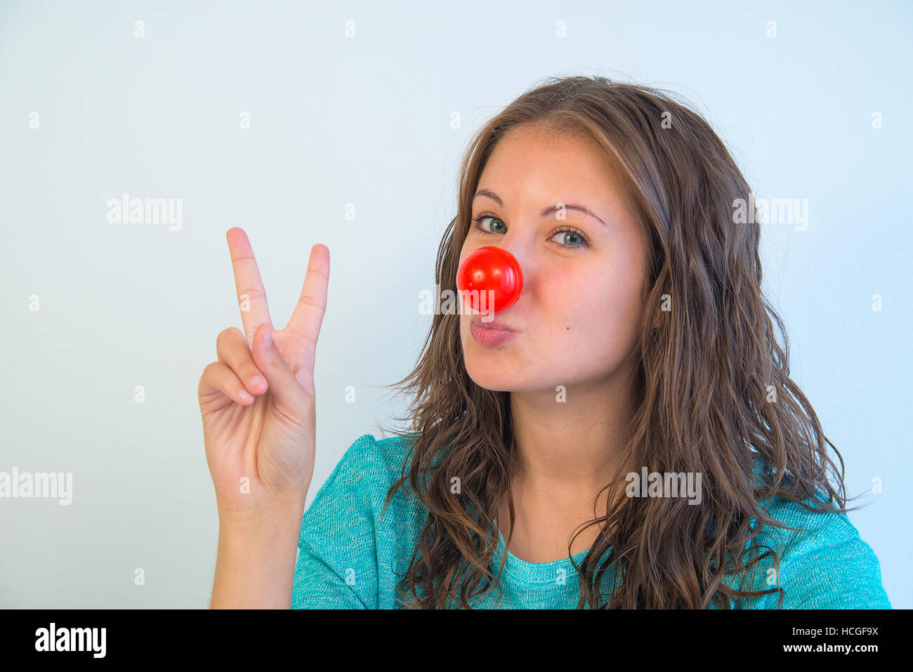 Ritratto di giovane donna che indossa un clown naso ed esprimendo la vittoria. Chiudere la vista. Foto Stock