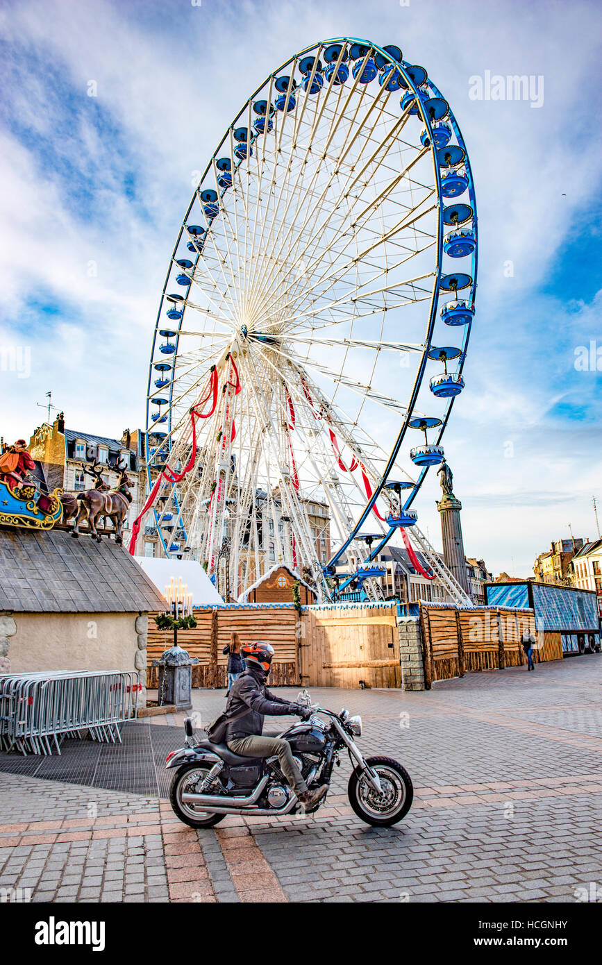 Ciclo del motore a Lille davanti alla ruota panoramica Ferris. A cavallo su un marciapiede pavimentato. Foto Stock