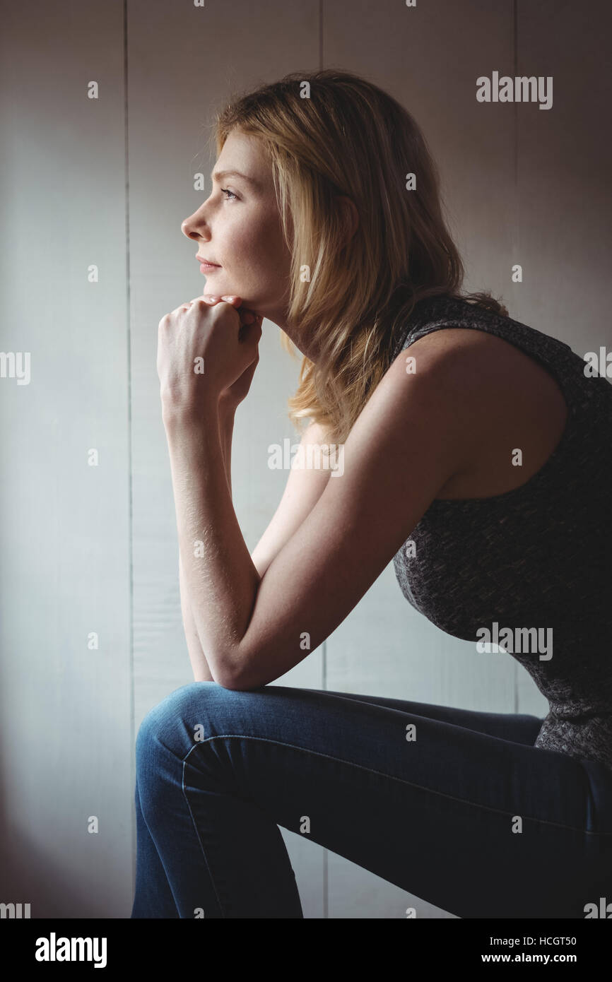 Premurosa donna seduta con la mano sul mento Foto Stock