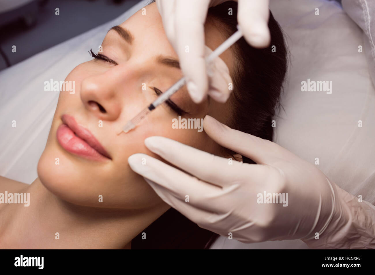 Paziente di sesso femminile riceve una iniezione sul suo viso Foto Stock