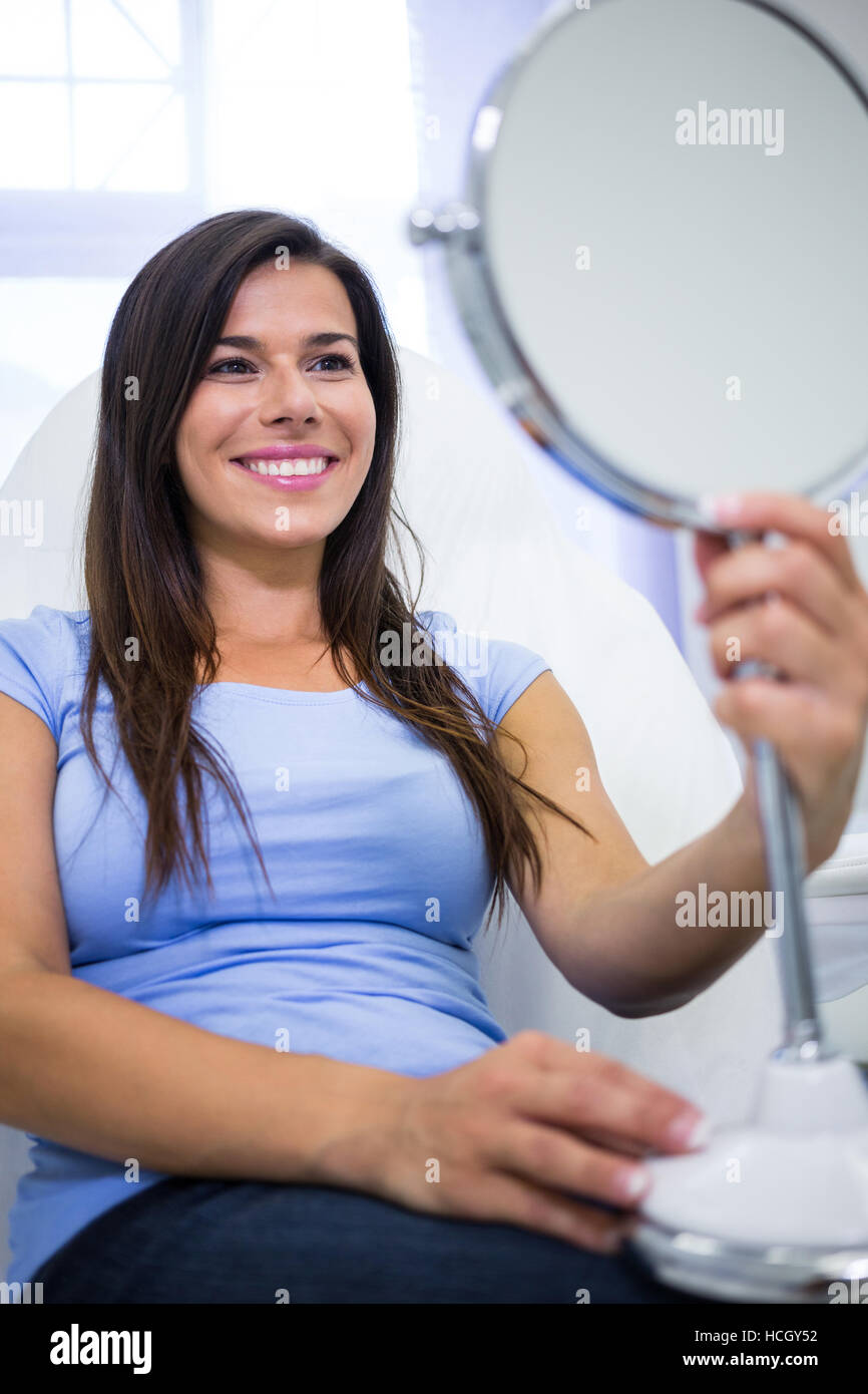 Paziente sorridente guardando nello specchio in cliniche Foto Stock