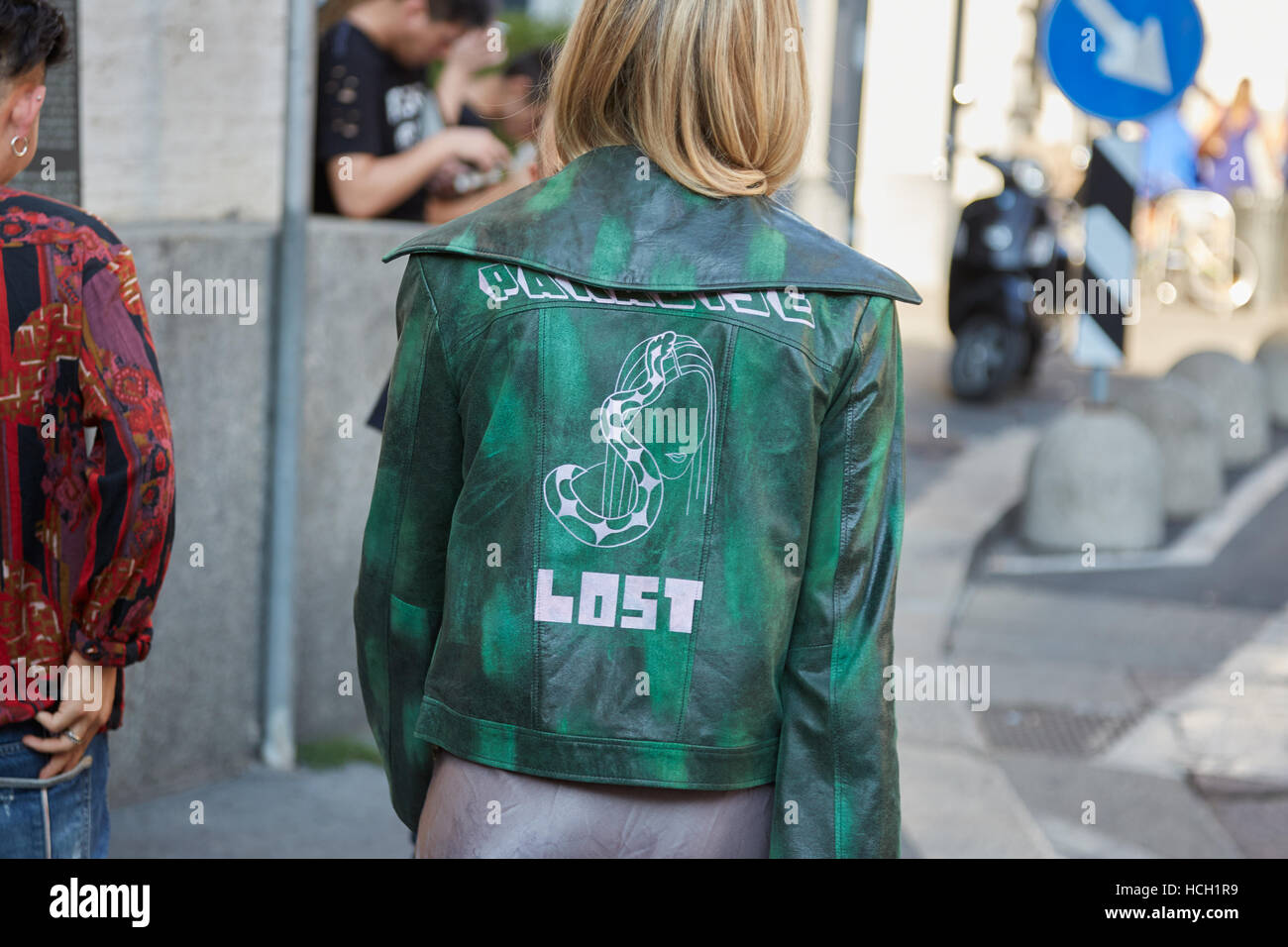 Donna con la giacca verde con Paradiso perduto la scrittura prima di Salvatore Ferragamo fashion show, la Settimana della Moda Milanese street style. Foto Stock