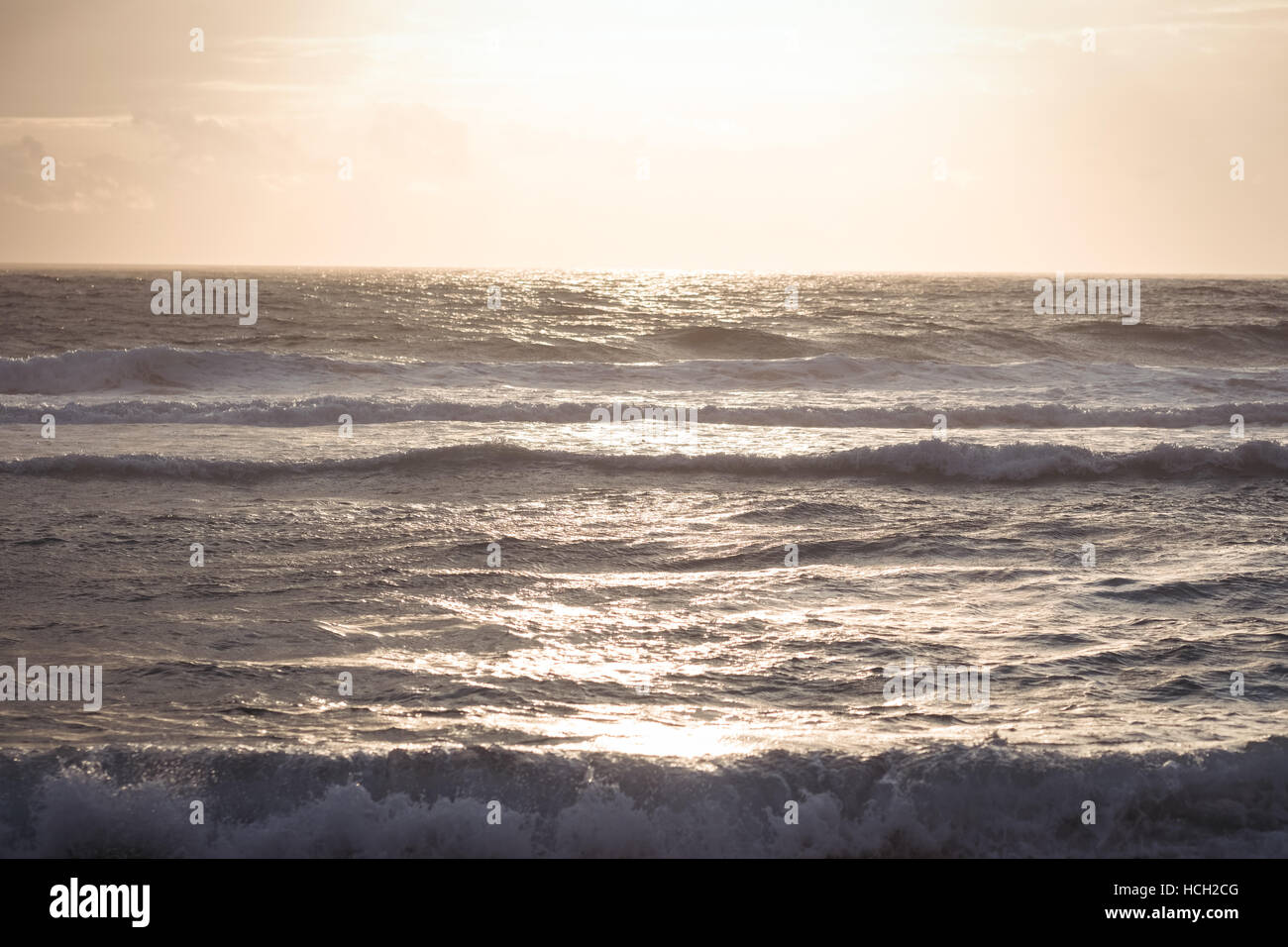 La luce del sole che riflette sulle onde in mare al tramonto Foto Stock