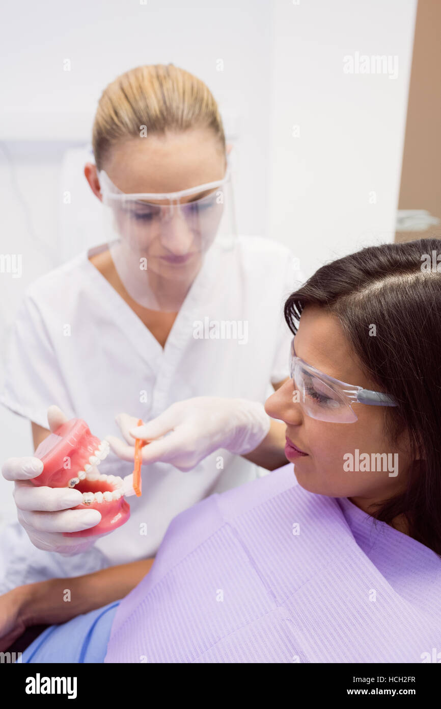 Dentista che mostra i denti di modello al paziente di sesso femminile Foto Stock