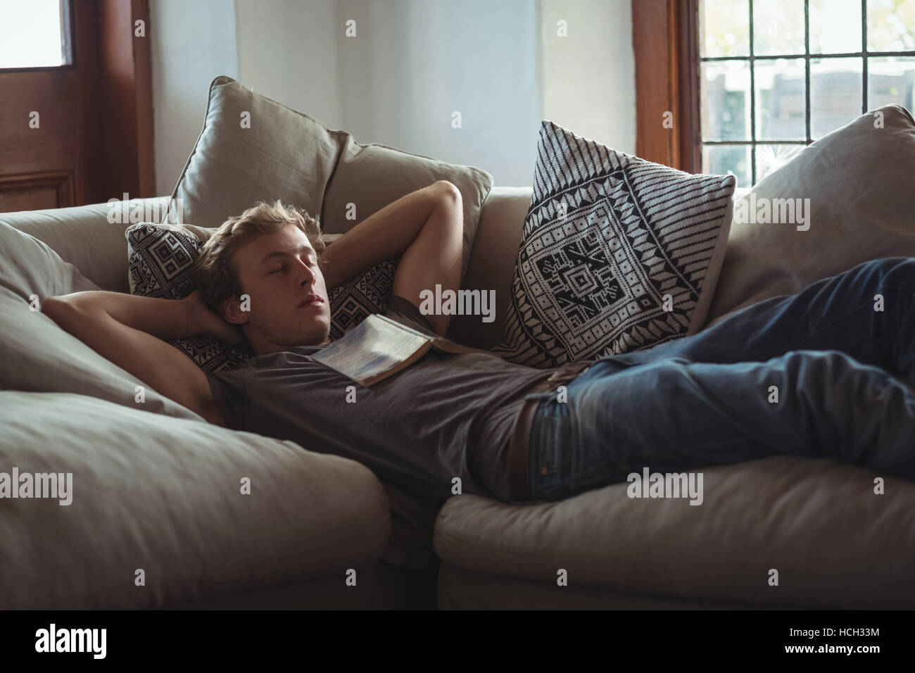 Uomo che dorme sul divano con un libro sul petto Foto Stock