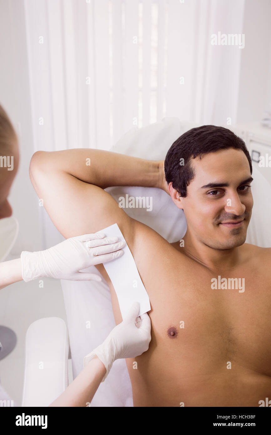 Medico di sesso maschile di sciolinatura la pelle del paziente Foto Stock