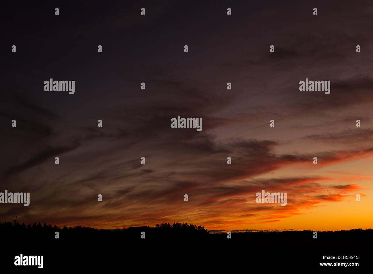 Nuvole angolata allo sbiadimento da arancio a nero al tramonto su una profila paesaggio. Foto Stock