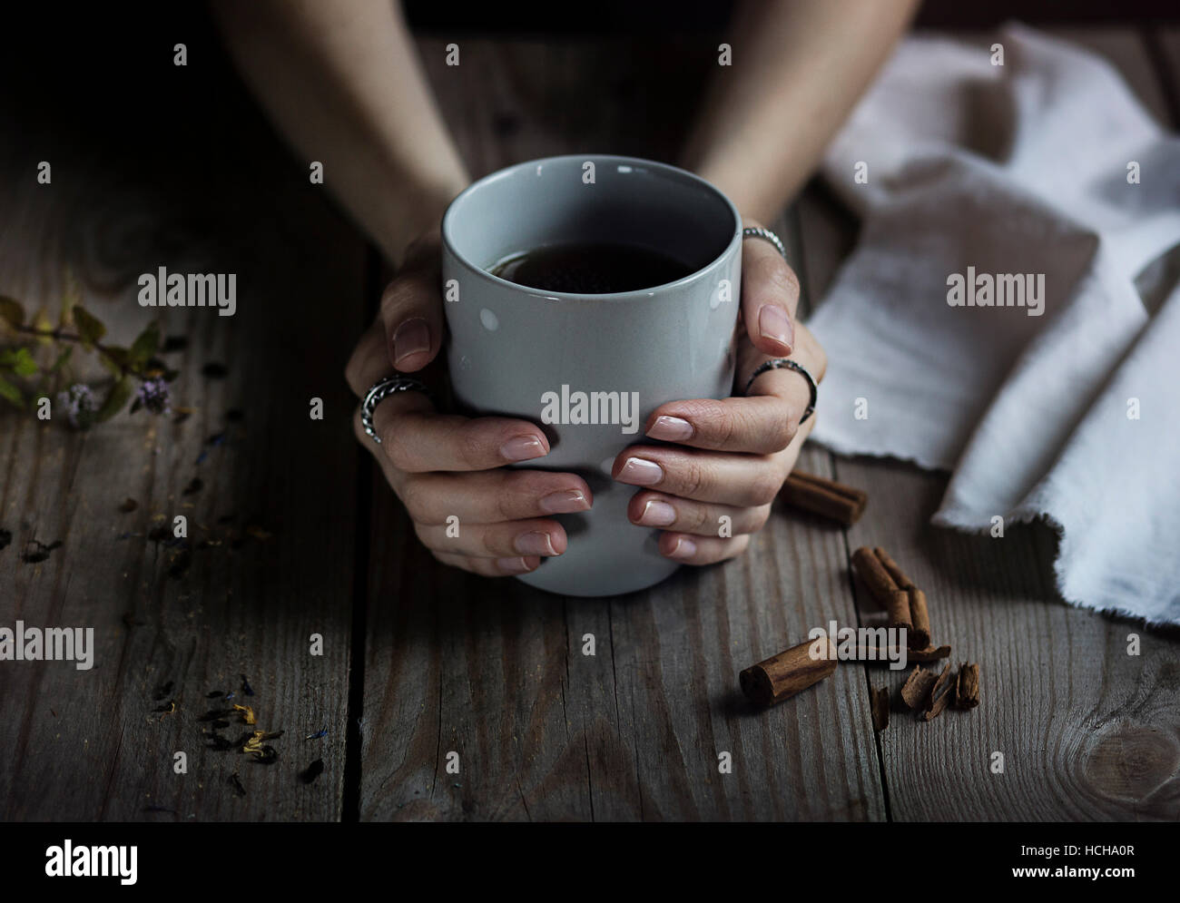Donna di mani tenendo una tazza di tè sul tavolo di legno Foto Stock Donna di mani tenendo una tazza di tè sul tavolo di legno Foto Stock