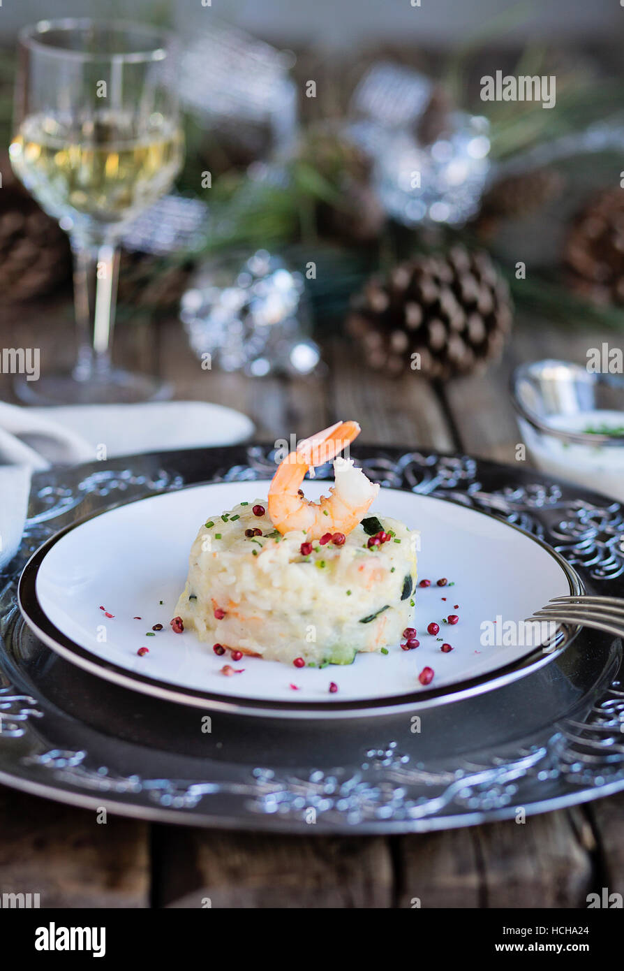 Scampi e zucchine risotto sul tavolo in legno con decorazioni di Natale Foto Stock