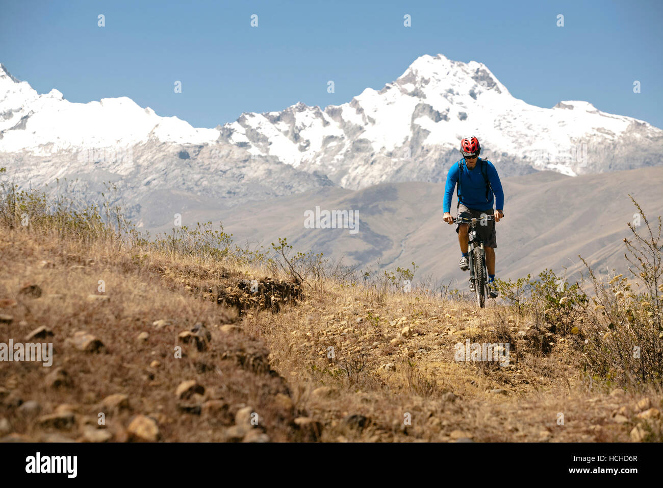 Un ciclista in sella alla sua mountain bike con alcuni picchi della Cordillera Blanca in retro. Huaraz, Perù. Foto Stock