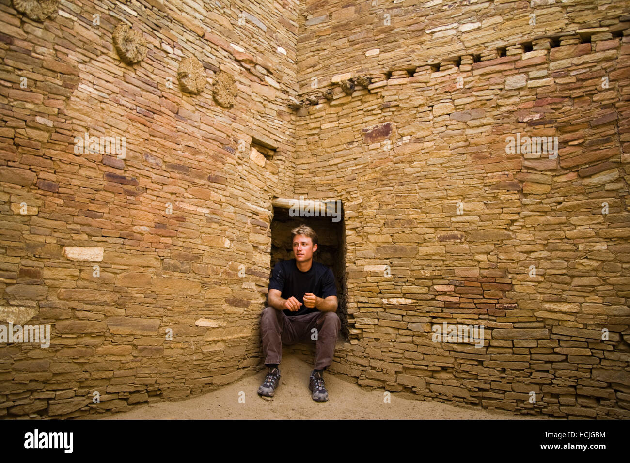 Scott Gilmore si siede in un piccolo vestibolo incorporato in uno dei muri di pietra del Pueblo Bonito, Chaco Canyon, Nuovo Messico. Foto Stock