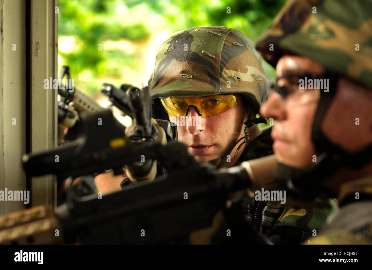 Una speciale selezione di armi e tattiche (SWAT) squadra dimostra come cancellare le camere. Gli ufficiali di polizia utilizzare armi semiautomatiche nonché indossare i caschi e occhiali di protezione per la sicurezza. Foto Stock