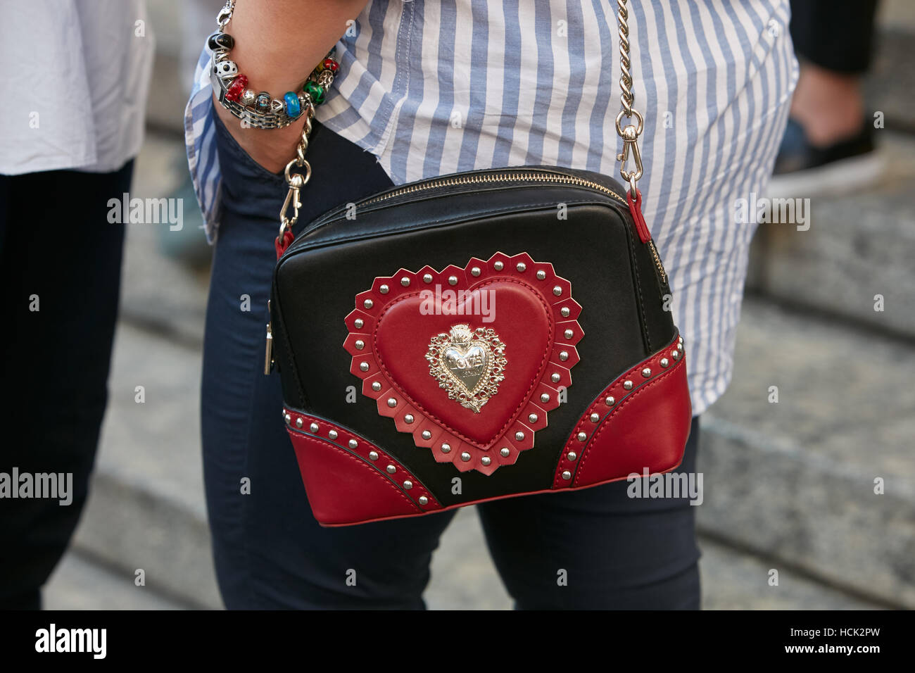 Donna con amore Moschino in nero e rosso borsa in pelle prima di Salvatore Ferragamo fashion show, la Settimana della Moda Milanese street style. Foto Stock