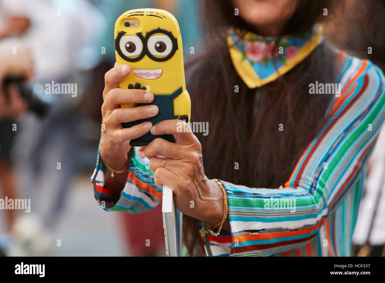 Donna con giallo Minion coperchio dello smartphone prima di Salvatore Ferragamo fashion show, la Settimana della Moda Milanese street style in settembre. Foto Stock