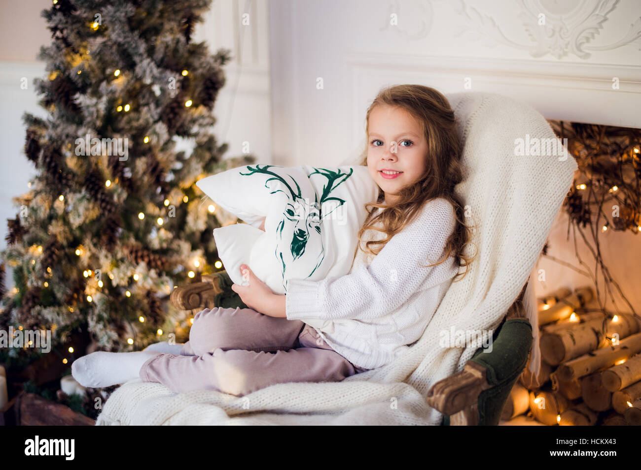 Piccola principessa sedersi sulla poltrona con i cervi cuscino da albero di  Natale a casa Foto stock - Alamy