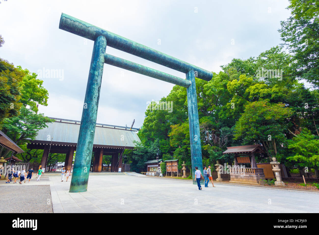 La gente camminare attraverso Daini angolata Torii gate shinmon alla porta di legno in ingresso al controverso Yasukuni sacrario scintoista Foto Stock