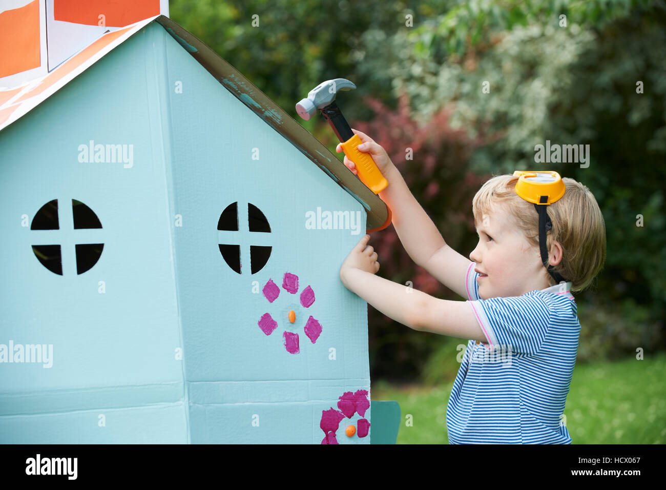 Ragazzo giovane fingendo di fissare Playhouse di cartone Foto Stock