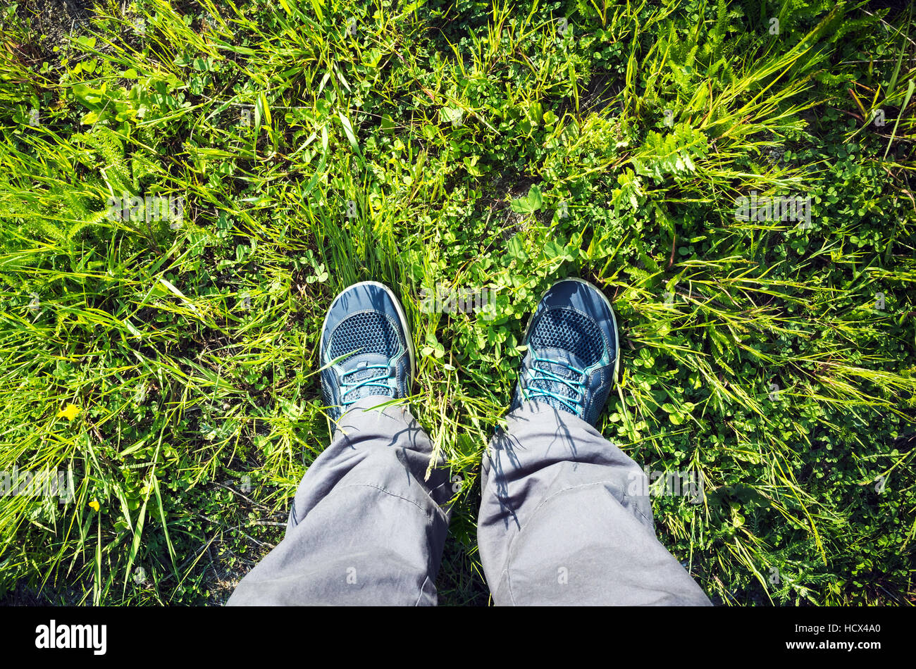 Piedini maschio in blu sport scarpe in piedi sul luminoso verde erba estiva Foto Stock