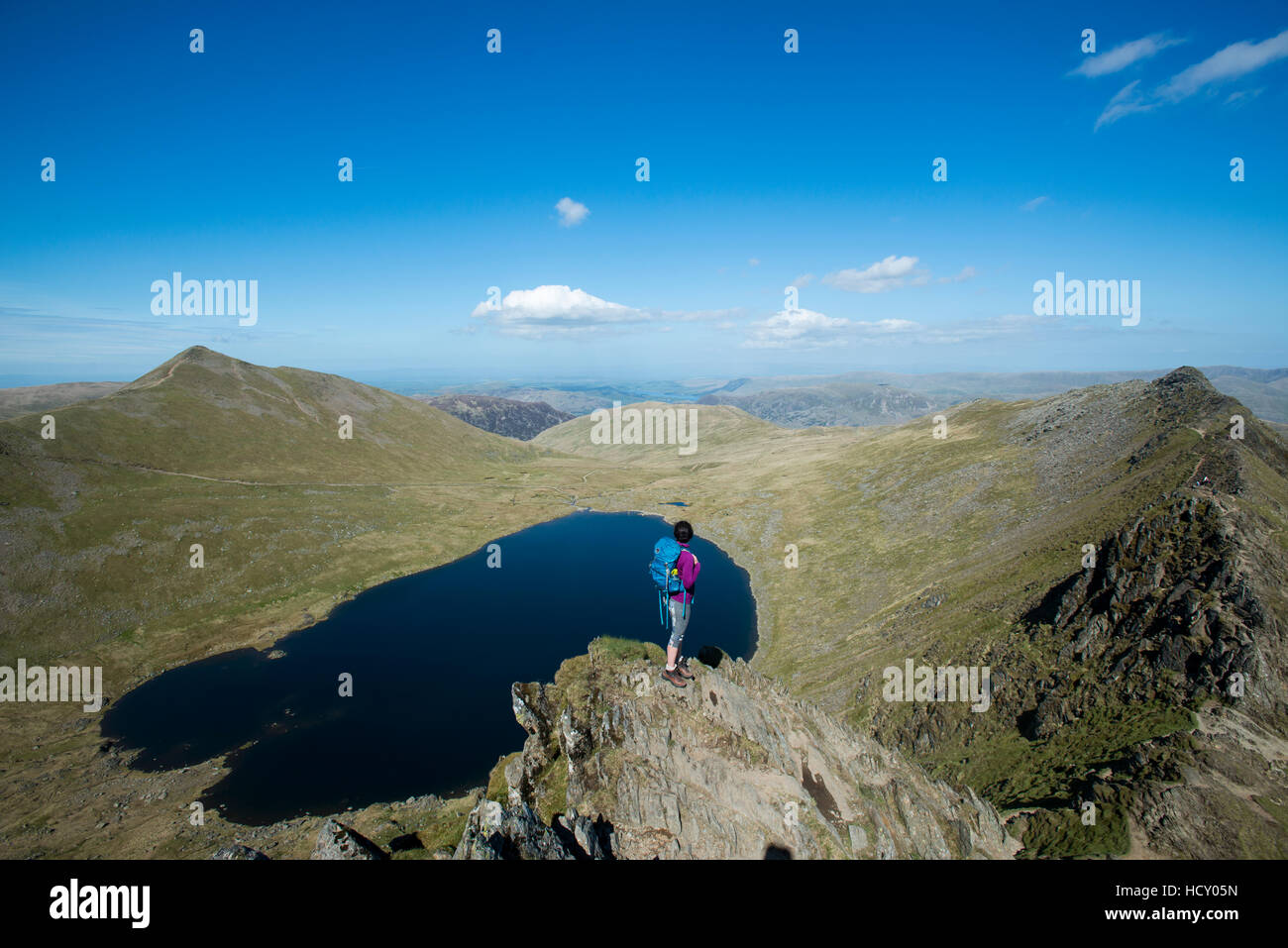 Una donna si erge sulla parte superiore del bordo di estensione con una vista di Red Tarn sotto, Parco Nazionale del Distretto dei Laghi, Cumbria, Regno Unito Foto Stock