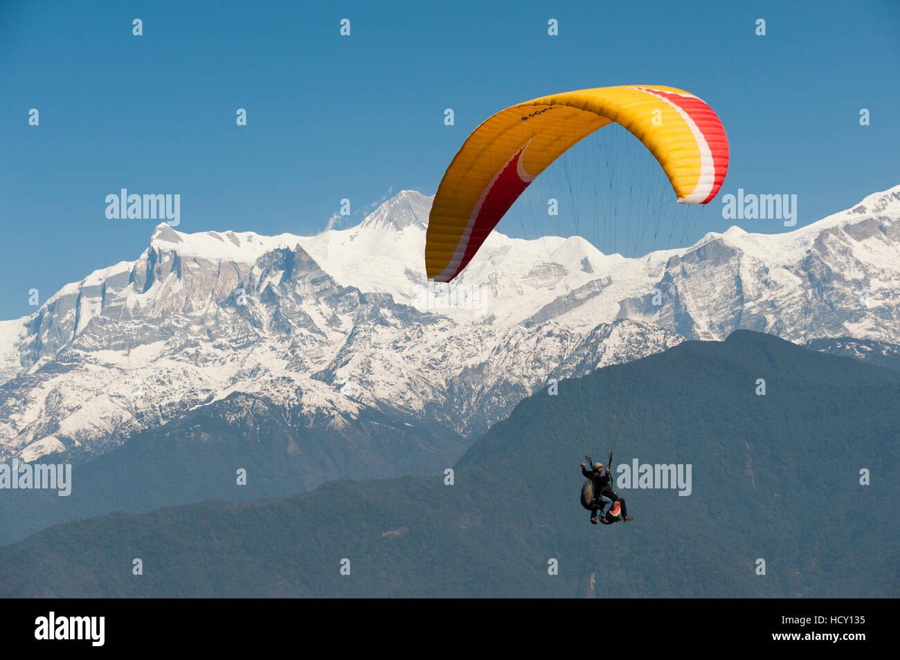 Un tandem di parapendio vola al di sopra di Pokhara con vedute del Annapurnas, Nepal Foto Stock
