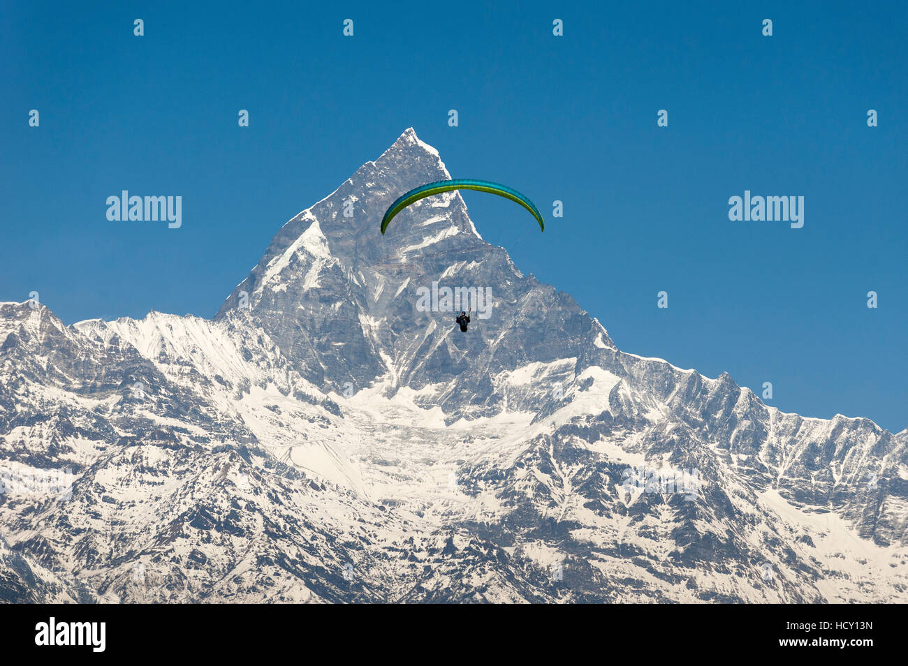 Un parapendio si blocca in aria con il picco drammatico di Machapuchare (coda di pesce della montagna) nella distanza, Nepal Foto Stock