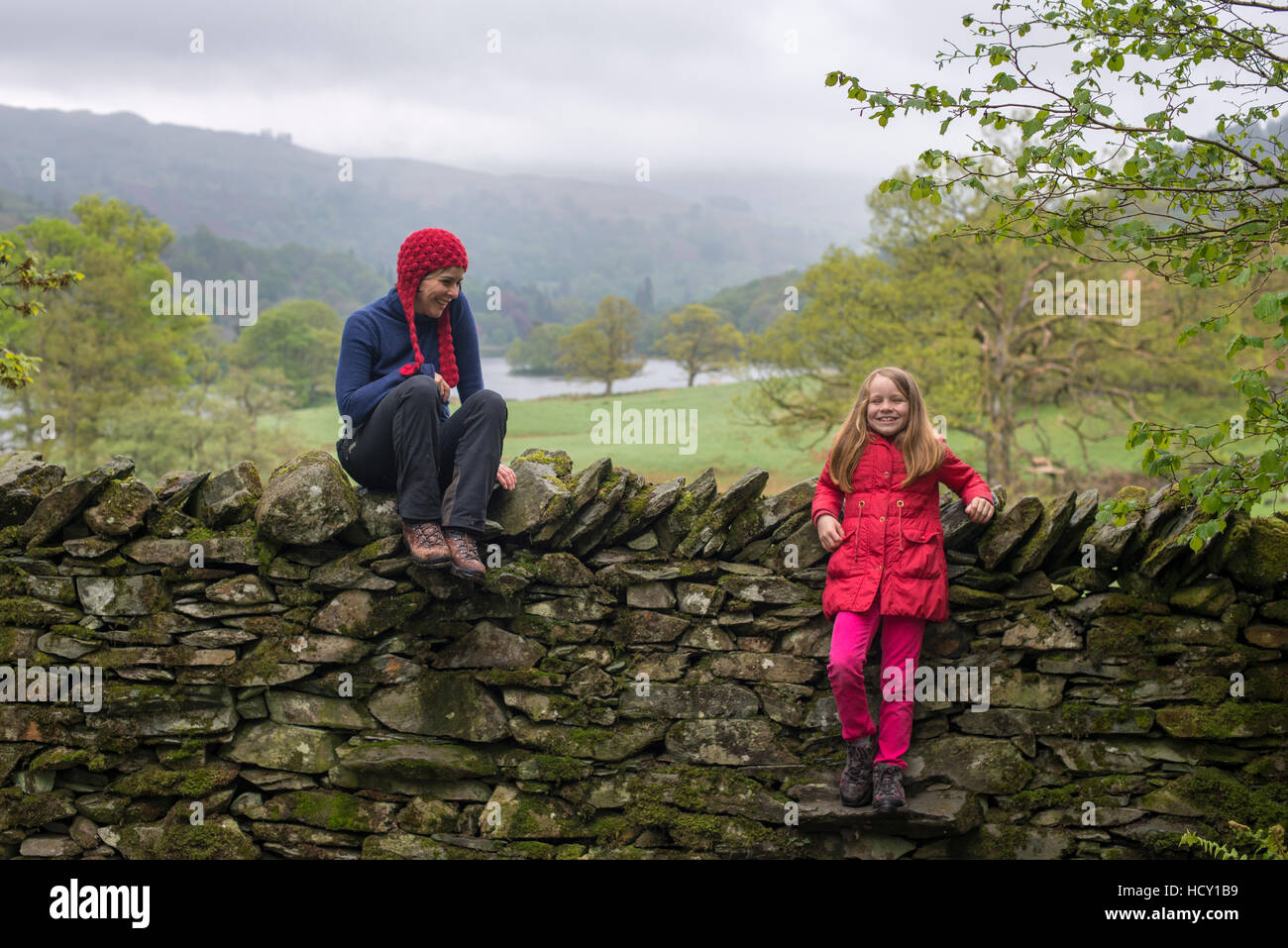 Madre e figlia resto a secco su un muro di pietra mentre è in vacanza nel distretto del lago, Cumbria, Regno Unito Foto Stock