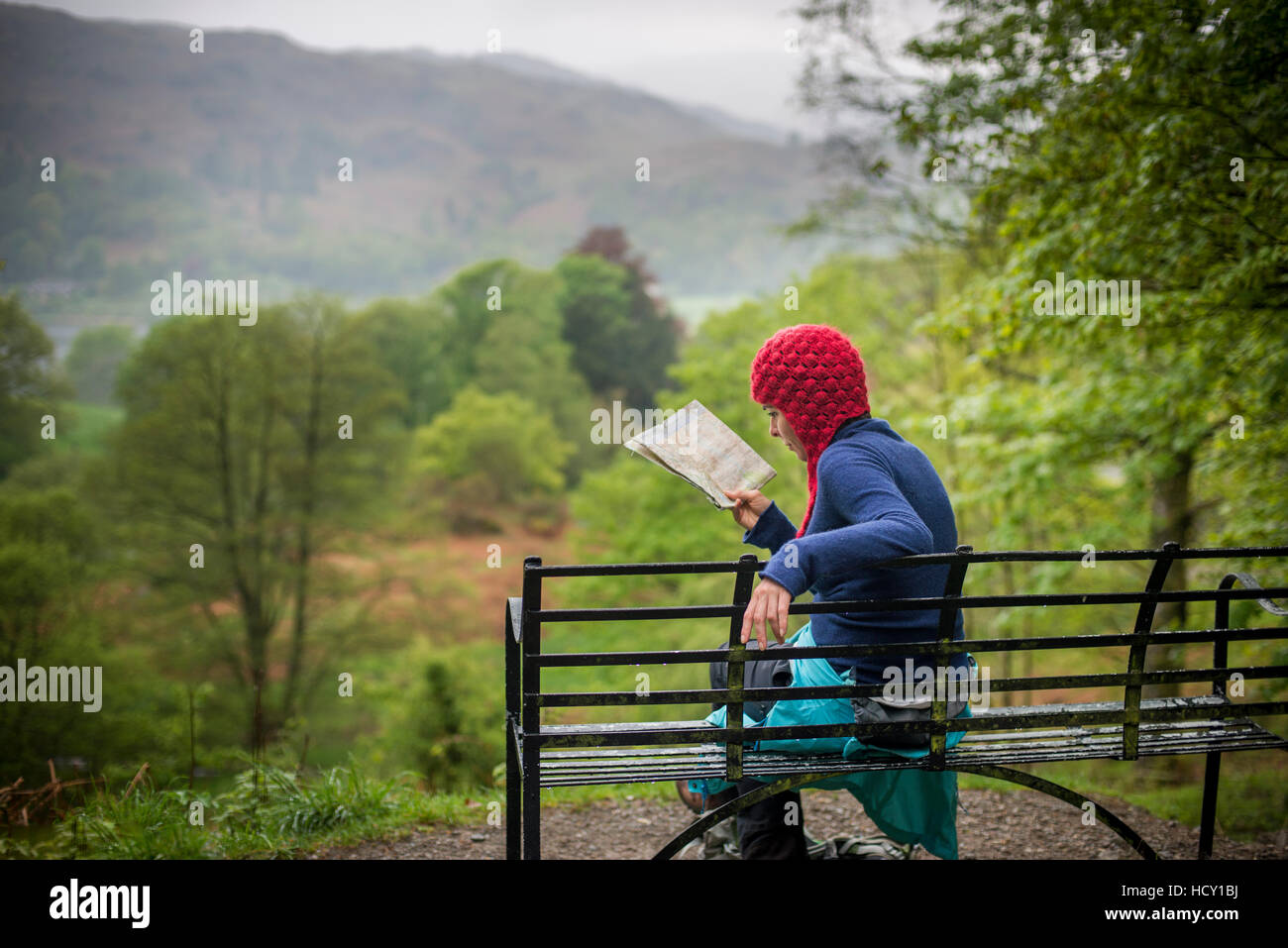 Una donna si appoggia su un banco di lavoro mentre si cammina nel distretto del lago vicino a Grasmere, Cumbria, Regno Unito Foto Stock