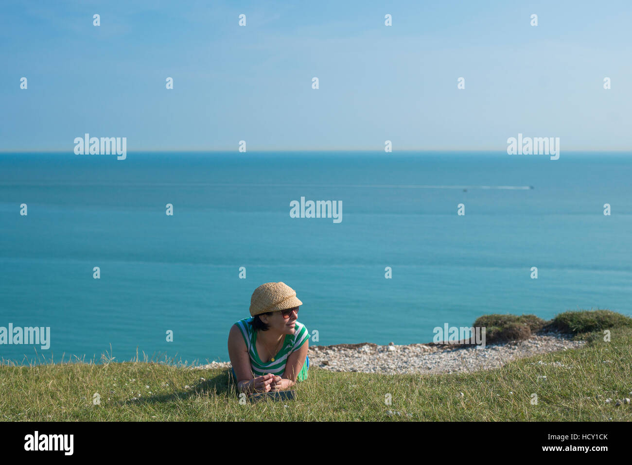 Una donna si trova sulle scogliere vicino a Beachy Head con vedute del mare in lontananza, East Sussex, Regno Unito Foto Stock