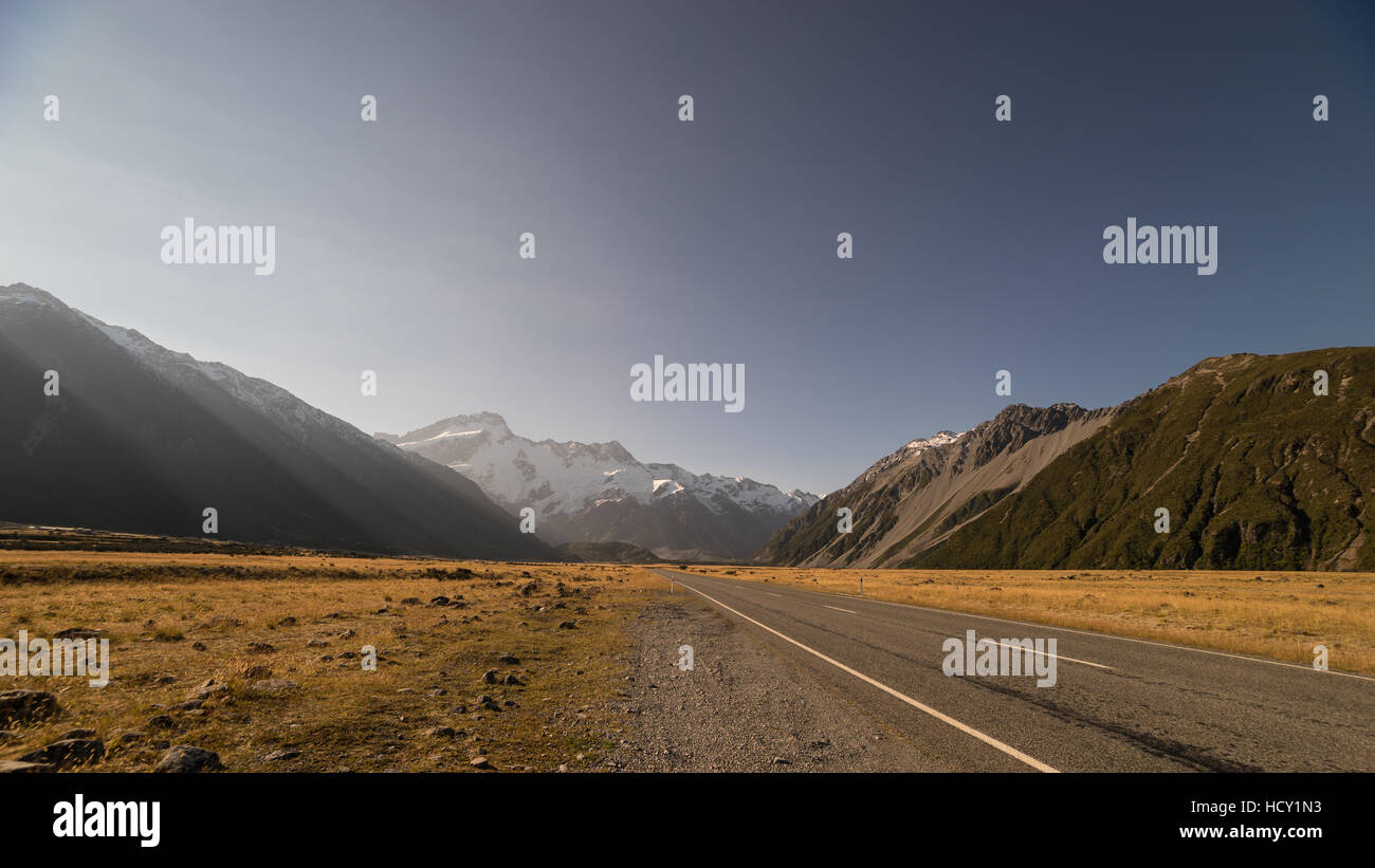 Nel tardo pomeriggio sun su una lunga strada diritta in montagna, Isola del Sud, Nuova Zelanda Foto Stock