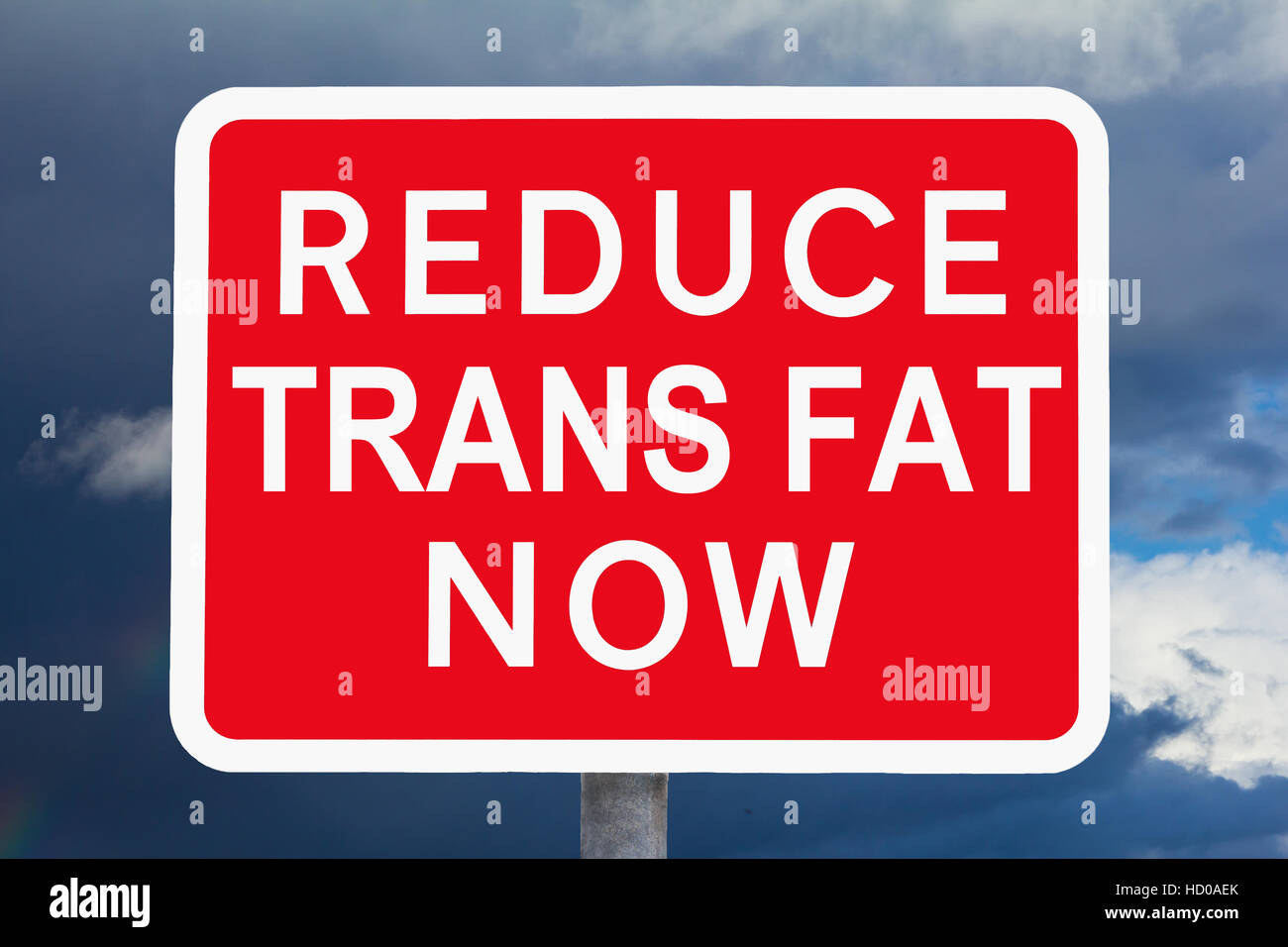 Segno bianco e rosso ridurre i grassi trans ora di fronte a un cielo scuro, simbolo per il rischio per la salute da mangiare un sacco di fast-food Foto Stock