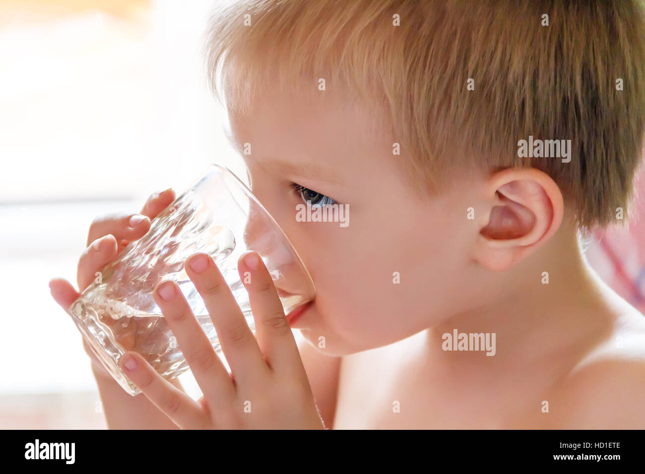 Foto del bambino biondo acqua potabile dal vetro Foto Stock