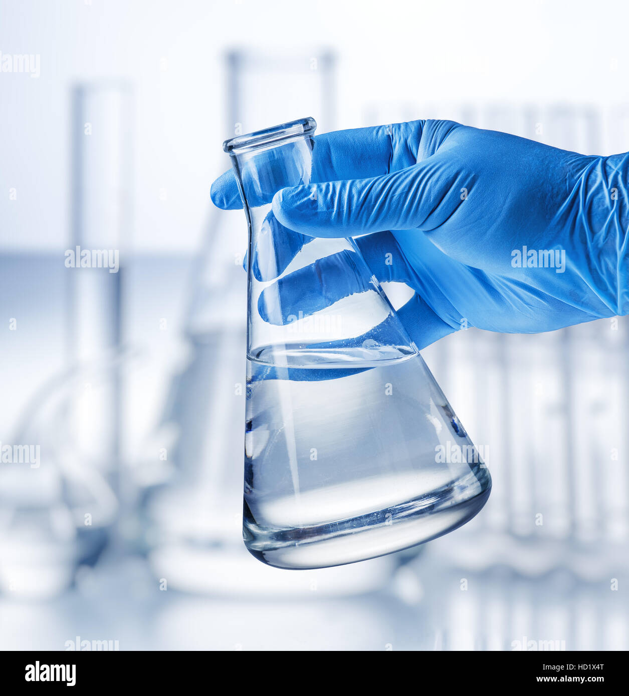 Bicchiere da laboratorio in analyst la mano nel guanto di plastica. Foto Stock