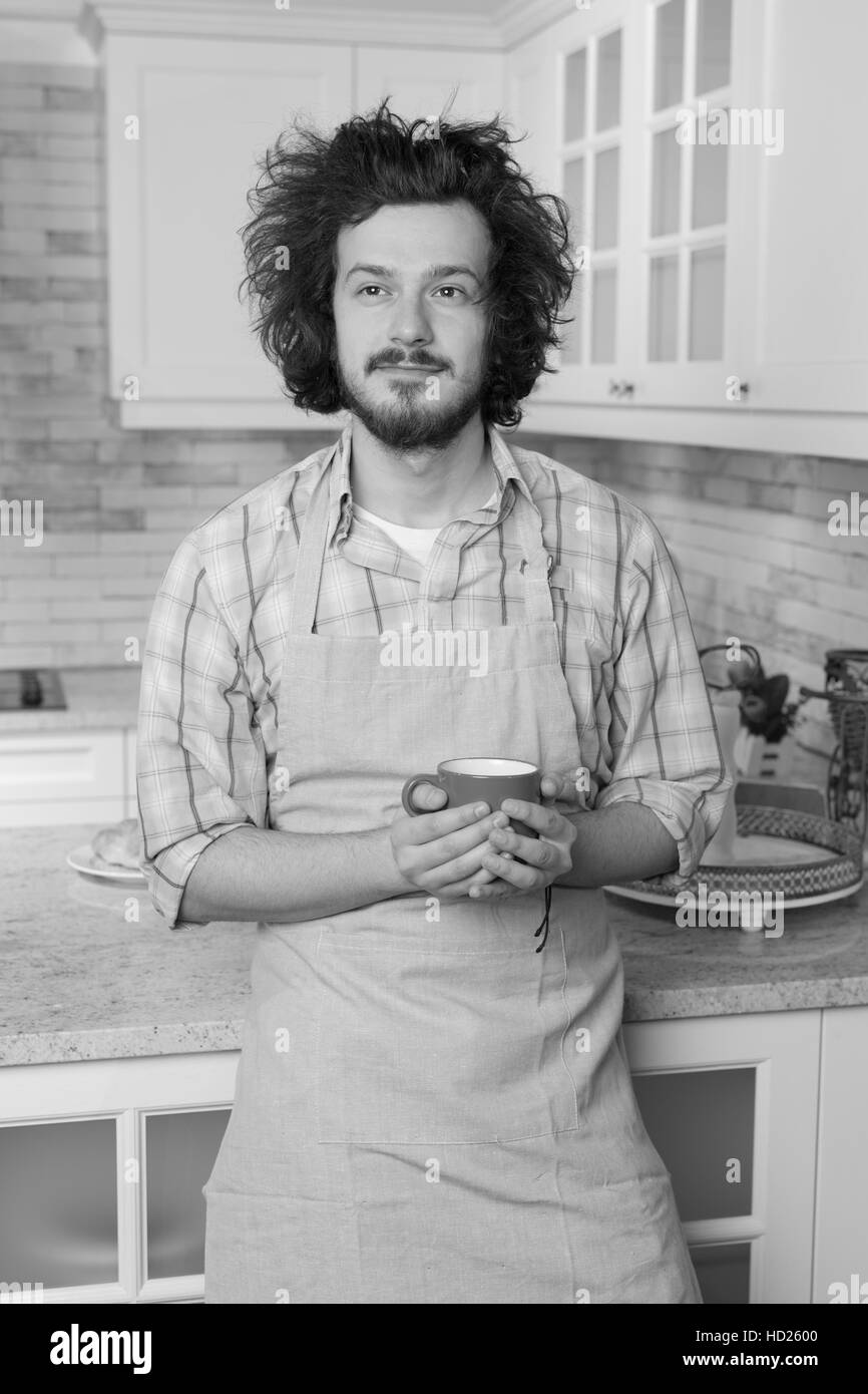 Buona ricerca uomo in un grembiule in fron di cucina a casa Foto Stock