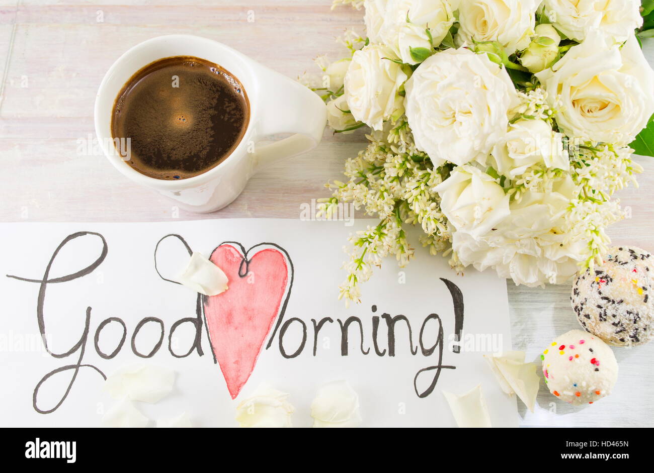 Rose bianche, caffè e buona mattina nota su un tavolo Foto Stock