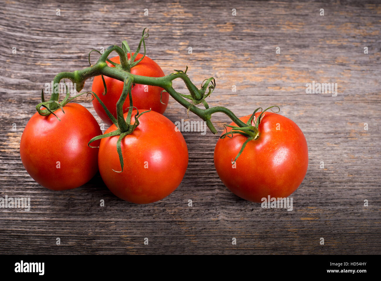Grappolo di pomodori sul tavolo di legno nella luce naturale Foto Stock